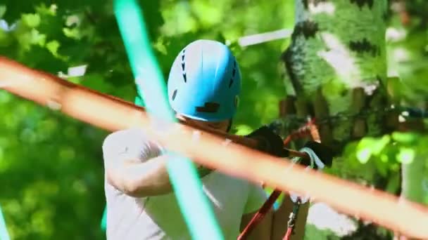 Seil-Abenteuer - Mann mit Tätowierung läuft vorsichtig auf der Hängeseilbrücke und hält das Oberseil mit den Händen — Stockvideo
