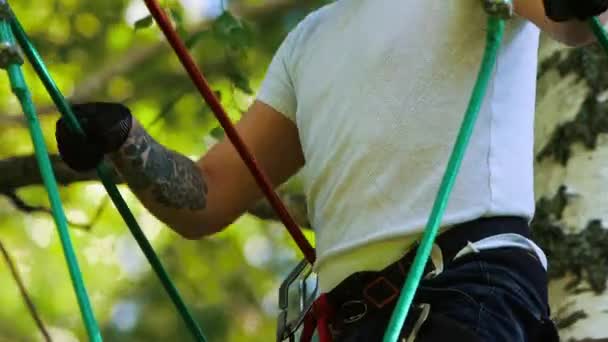 Aventura de corda - homem de gengibre com tatuagem caminha cuidadosamente na ponte de corda suspensa — Vídeo de Stock