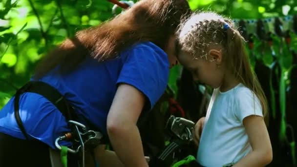 Rep äventyr - en kvinnlig instruktör sätter på sig försäkring hängen på midjan av en liten flicka — Stockvideo