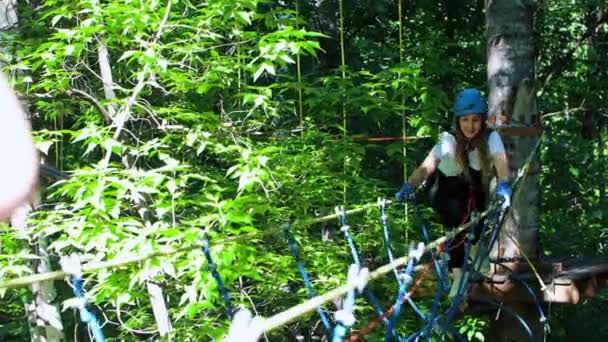 Aventura de cuerda extrema - mujer sonriente caminando en el puente de cuerda colgante en el parque — Vídeo de stock