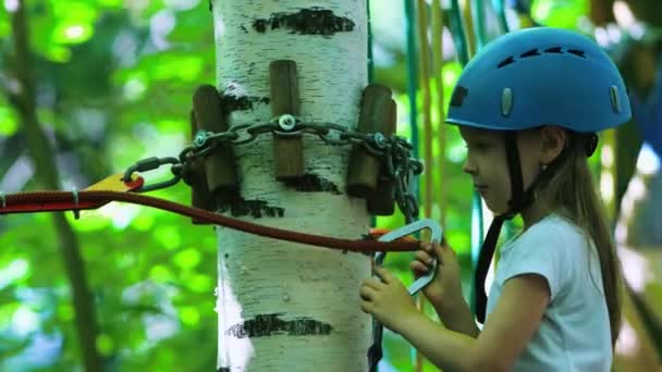 Seil-Abenteuer - ein kleines Mädchen auf einer Seilbrücke mit Versicherungsgurt — Stockvideo