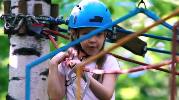 Seilabenteuer im Park - ein kleines Mädchen bewegt sich über die Seilbrücke — Stockvideo