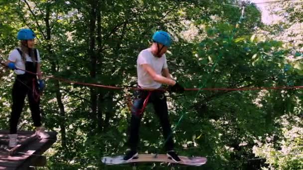 Extrémní lano dobrodružství v parku - muž pohybující se na laně pomocí skateboardu — Stock video