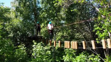 Parktaki sıra dışı halat macerası. İpte yürüyen ve elinde sigortayla kürsüye çıkan adam.
