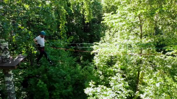 Extremes Seil-Abenteuer im Park - Mann läuft vorsichtig auf dem Seil zwischen zwei Stand mit einer Versicherung — Stockvideo