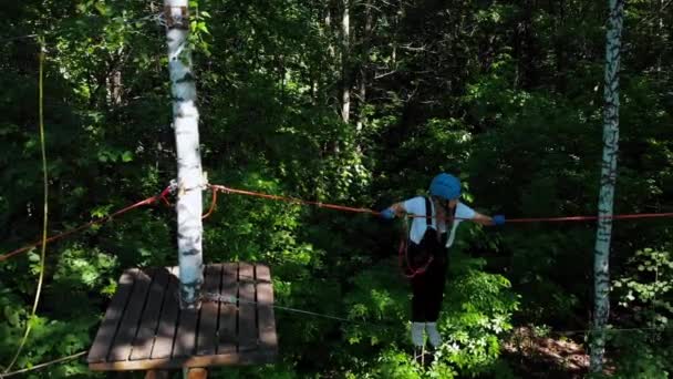 Extreem touw avontuur in het park - vrouw loopt op het touw tussen twee staan met een verzekeringsriem om haar middel — Stockvideo