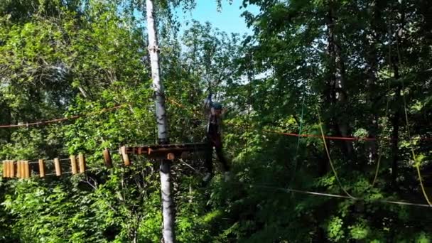 夏の公園での極端なロープの冒険-女性は腰に保険ベルトで2つのスタンドの間のロープを歩く — ストック動画