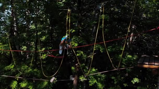 Aventura de corda extrema no parque mulher andando na corda entre o suporte e seu marido com um cinto de seguro na cintura — Vídeo de Stock