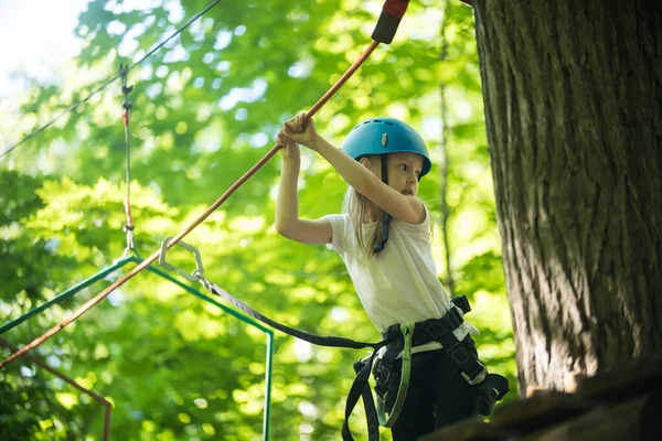 Touw avontuur - een klein meisje staan op hoog bij de boom en houden door de touwen met haar handen — Stockfoto
