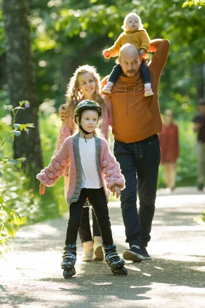 Joven familia feliz de padres y dos niños pequeños caminando en el bosque mientras que el verano — Foto de Stock