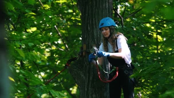 Aventura de corda - uma mulher anexando o gancho à corda de seguro na árvore — Vídeo de Stock