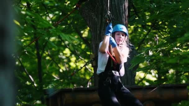 Seil-Abenteuer - lächelnde blonde Frau, die mit ihrem Versicherungsgürtel auf dem Seil nach unten rutscht — Stockvideo