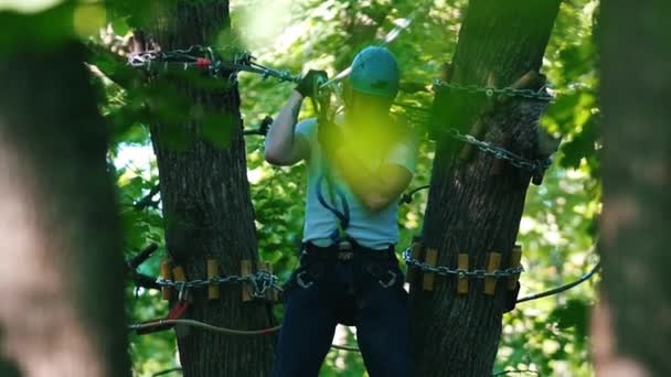 Um homem tendo uma aventura de corda na floresta com seguro total descendo usando seu cinto de seguro — Vídeo de Stock