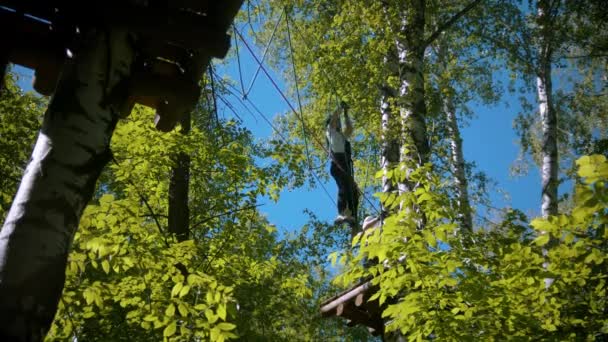 Man and woman crossing the rope bridge - an entertainment attraction in the green park — Stock Video