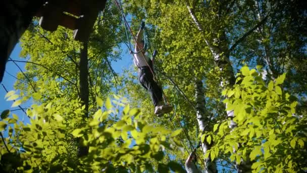 Férfi és nő átkelnek a kötélhídon - szórakoztató attrakció a zöld erdőben — Stock videók