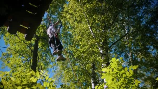 Een vrouw die de touwbrug oversteekt - een attractie in het bos — Stockvideo