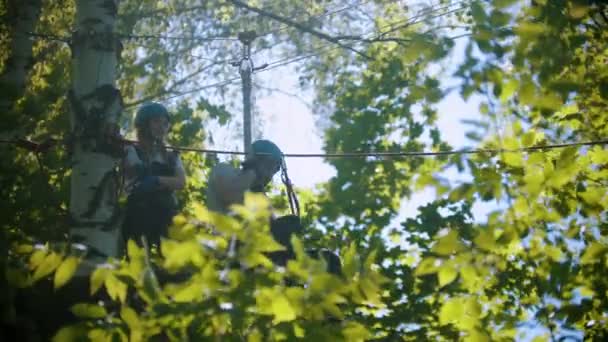 녹색 숲 속에서 오락을 즐기는 남녀 - 보험 벨트 를 사용하여 밧줄을 타고 미끄러져 내려오는 남자 — 비디오