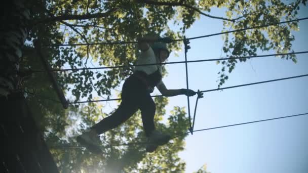 Mujer que tiene una atracción de entretenimiento en el bosque verde - cruzando el puente de cuerda — Vídeo de stock