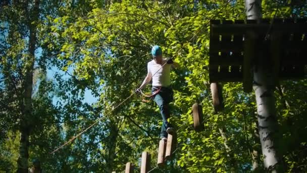 L'uomo che attraversa una costruzione della corda e ceppi - un'attrazione di intrattenimento nella foresta verde — Video Stock