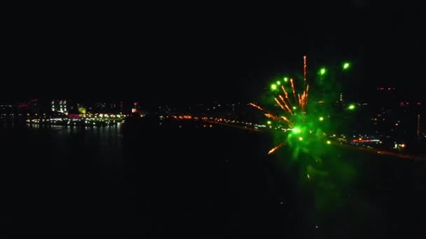 Fuegos artificiales brillantes que explotan en el aire sobre un fondo del río y la ciudad nocturna — Vídeos de Stock