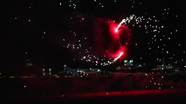 Fuegos artificiales ardiendo en la playa por la noche - fuegos artificiales rojos girando y esparce destellos — Vídeos de Stock