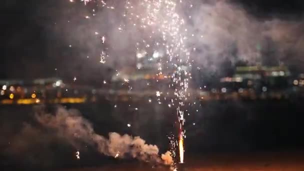 Pequenos fogos de artifício brancos e verdes queimando e explodindo na praia e produz fumaça — Vídeo de Stock