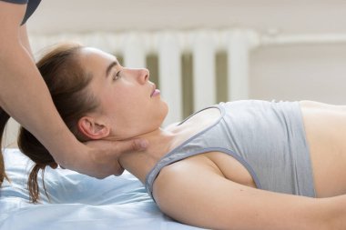 Osteopat tedavisi. Tıp hocası genç bir kadının kafasını yastığa koyuyor.