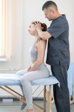 Osteopati tedavisi gören genç bir kadın. Kanepede oturan bir kadın. Ve efendi boynunu düzeltiyor.