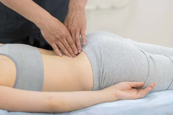 Молодая женщина, проходящая лечение остеопатии - массаж поясницы — стоковое фото