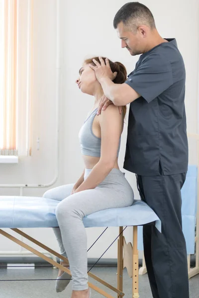 Junge Frau in Osteopathie-Behandlung - Frau sitzt auf der Couch und der Meister justiert ihren Hals — Stockfoto