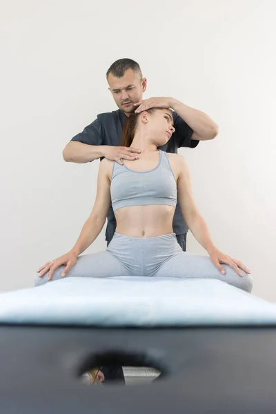 Chiropractie behandeling - jonge vrouw zittend op de bank - de arts draait haar hoofd naar de zijkant — Stockfoto