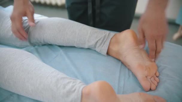 Mujer que recibe un tratamiento osteópata: el médico le presiona los pies y la rodilla — Vídeo de stock