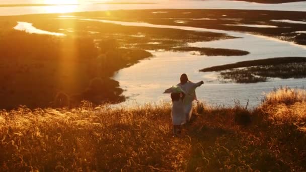 Jonge moeder met haar dochter rennen op de heuvel en spelen met de vlieger bij zonsondergang — Stockvideo