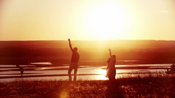 明るいオレンジ色の夕日ながら、若い家族がフィールドで遊んでいます-父はカイトを保持 — ストック動画