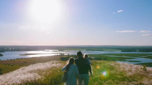 Jeune famille heureuse de quatre personnes debout sur le terrain et profitant de la vue — Video