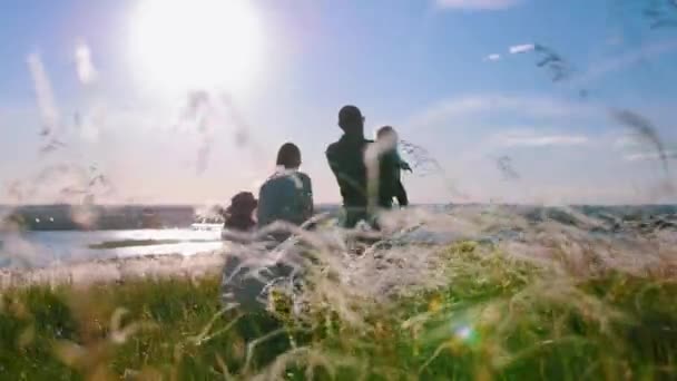 Młoda rodzina składająca się z czterech osób stojąca na boisku i ciesząca się widokiem — Wideo stockowe