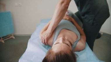 Osteopatik tedavi gören bir kadın. Doktor vücudunu iterken kanepede yatıyor.