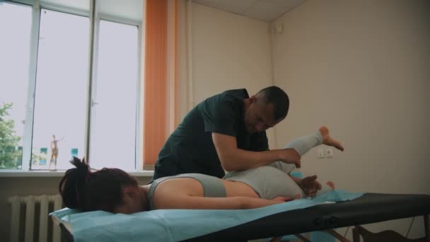 Frau in osteopathischer Behandlung - der Arzt wärmt das Bein der jungen Frau — Stockvideo