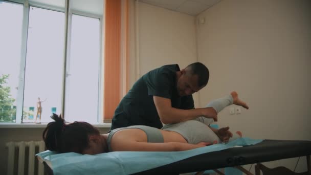 La mujer que tiene un tratamiento osteopático - el médico que calienta la pierna de la mujer joven — Vídeos de Stock