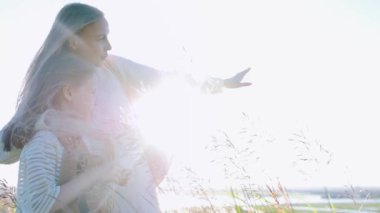 Genç anne kızıyla birlikte sahada duruyor ve ileriye bakıyor - onunla konuşuyor.