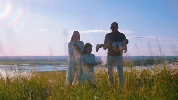 Молодая семья из четырех человек, стоящая на поле — стоковое видео
