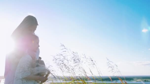 Ung mor står på planen med sin dotter i dagsljus — Stockvideo