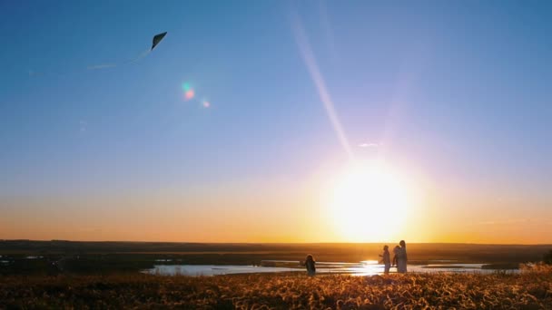 Jonge familie spelen met een vlieger op de heuvel - oranje zonsondergang — Stockvideo