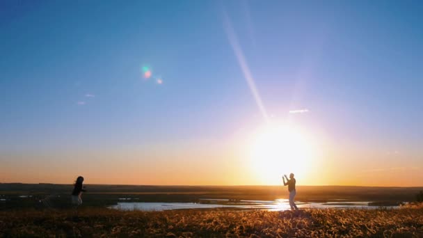 Jeune famille jouant avec un cerf-volant sur la colline au début du coucher du soleil - père menant le cerf-volant et petite fille courant sur le terrain — Video