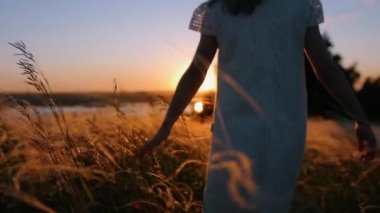 Küçük bir kız tarlada duruyor ve usulca kulaklara dokunuyor.