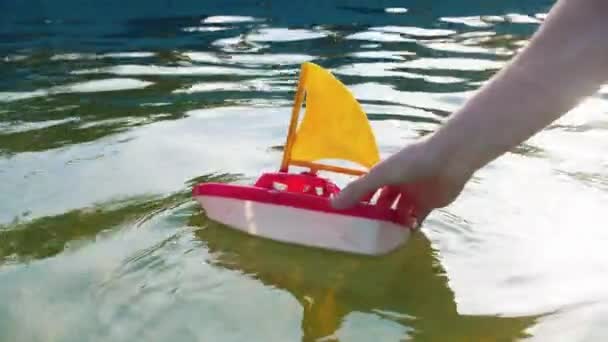 Main d'un jeune jouant avec un bateau jouet — Video