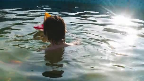 Young man playing with a yellow toy boat in the swimming pool — Stock Video