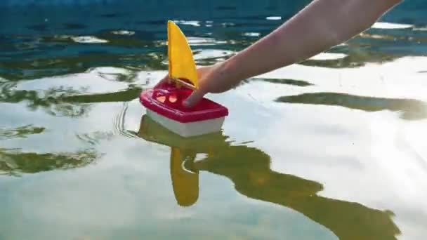 Hand van een jongeman verdrinkt een speelgoedschip — Stockvideo