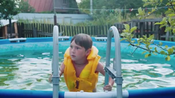 一个小男孩从一个充气游泳池里走出来 — 图库视频影像