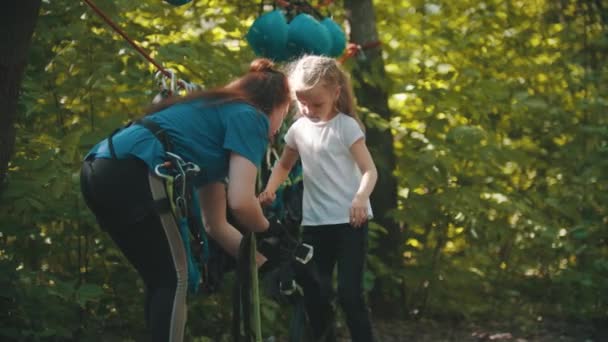 Femme instructrice aidant une petite fille à mettre la ceinture d'assurance — Video